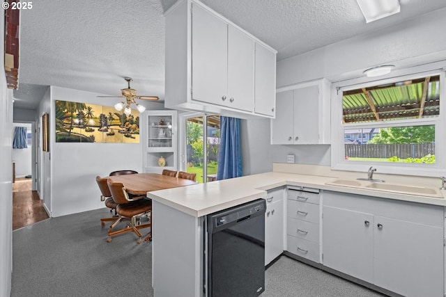 kitchen featuring a sink, a peninsula, black dishwasher, a textured ceiling, and light countertops