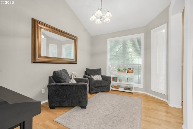 living area featuring a chandelier, baseboards, lofted ceiling, and light wood finished floors