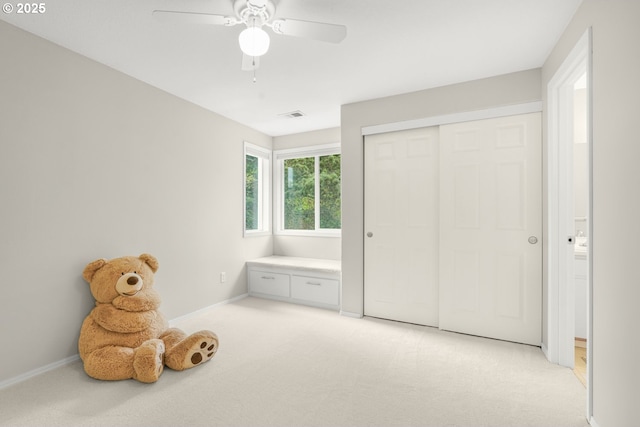 interior space with visible vents, a ceiling fan, baseboards, and light carpet