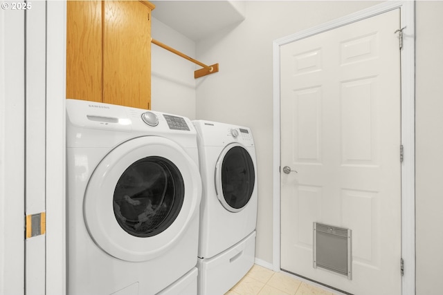 clothes washing area featuring light tile patterned flooring, cabinet space, and washing machine and clothes dryer