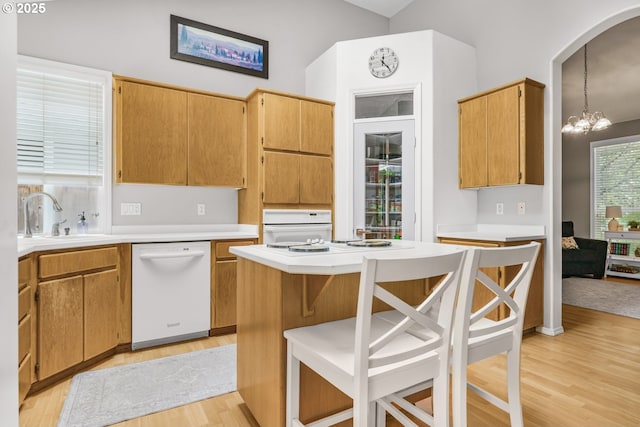 kitchen with light countertops, light wood-type flooring, a sink, and dishwasher