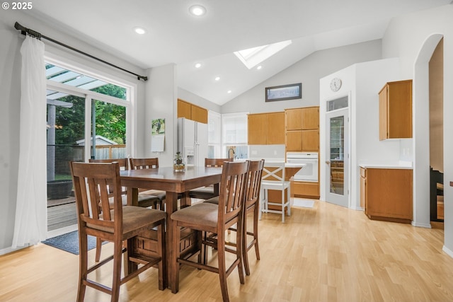 dining area with recessed lighting, a skylight, high vaulted ceiling, and light wood-type flooring