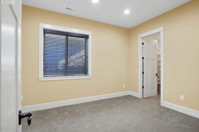 carpeted empty room featuring recessed lighting, visible vents, and baseboards