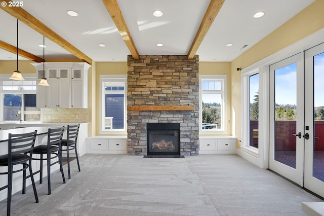 living room featuring a wealth of natural light, beam ceiling, and french doors