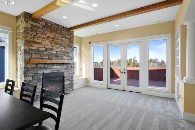 carpeted living room featuring ornate columns, a wealth of natural light, and a stone fireplace