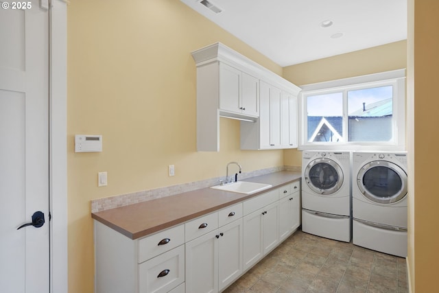 laundry area with visible vents, separate washer and dryer, a sink, and cabinet space