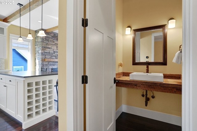 bathroom with beam ceiling, a sink, and wood finished floors