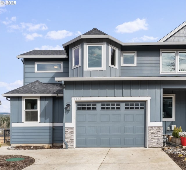 view of front of property with a garage, stone siding, driveway, and roof with shingles