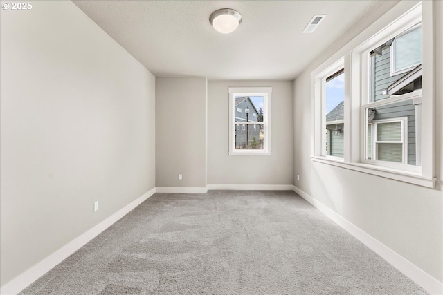 carpeted spare room featuring visible vents and baseboards