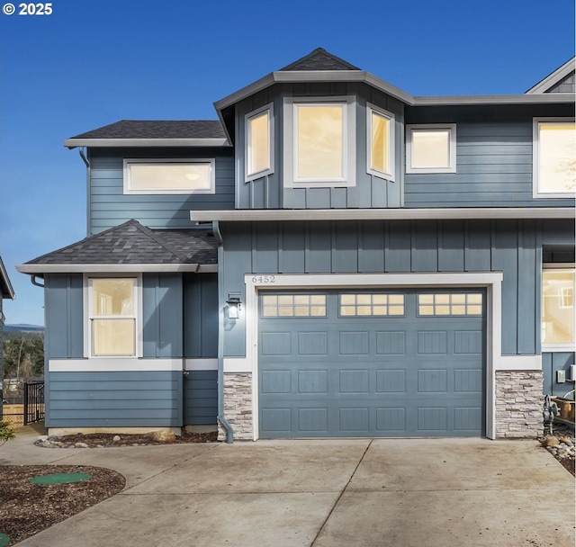 view of front of house featuring stone siding, concrete driveway, roof with shingles, and an attached garage