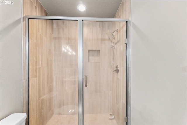 bathroom featuring a stall shower, a textured ceiling, and toilet