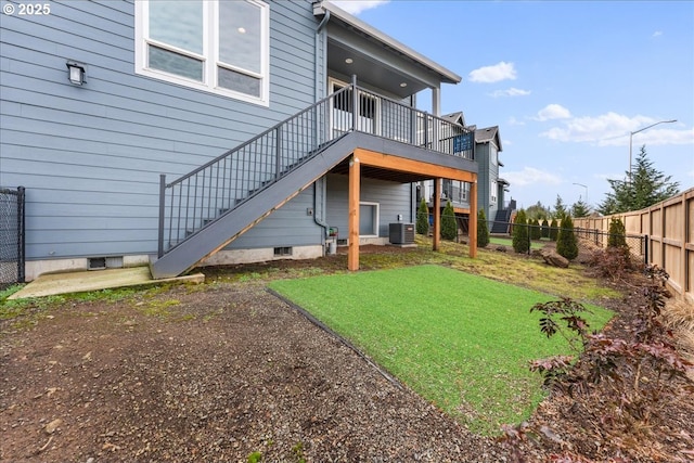 rear view of property with a fenced backyard, a lawn, stairway, and central air condition unit