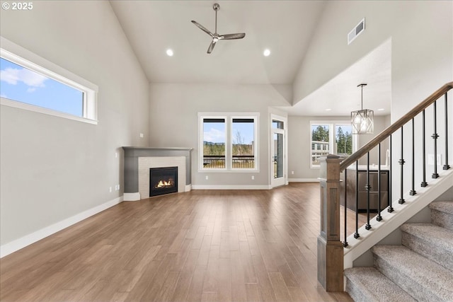 unfurnished living room with high vaulted ceiling, visible vents, stairway, and wood finished floors