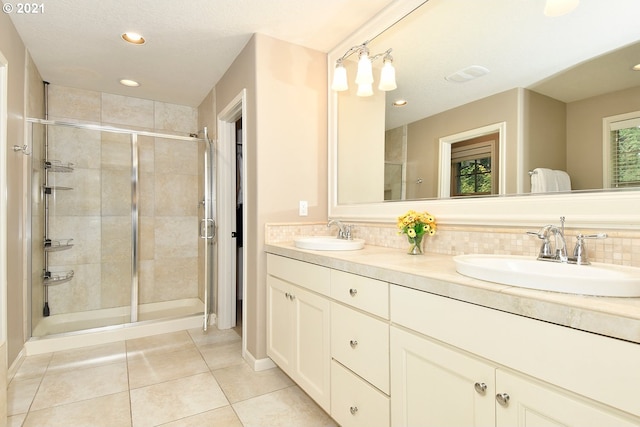 bathroom with tasteful backsplash, vanity, an enclosed shower, and tile patterned flooring