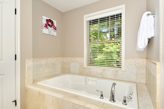 bathroom with tiled bath and a healthy amount of sunlight