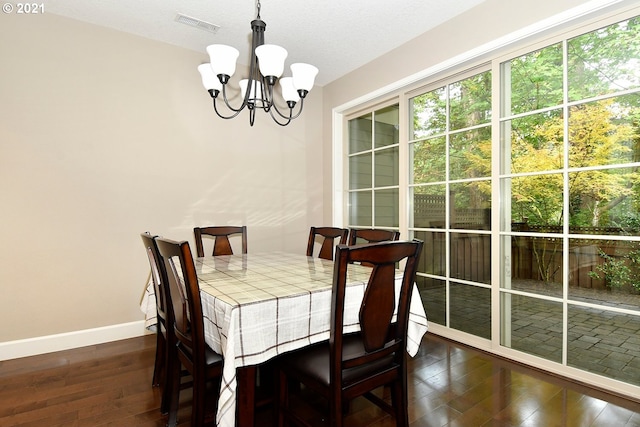 dining space with dark wood-type flooring and a chandelier