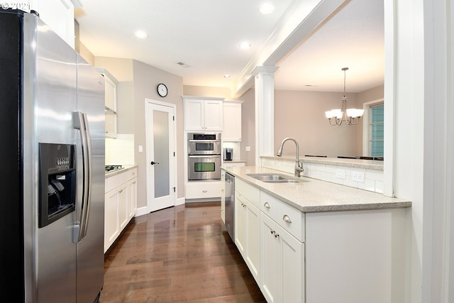 kitchen featuring sink, hanging light fixtures, appliances with stainless steel finishes, light stone countertops, and white cabinets