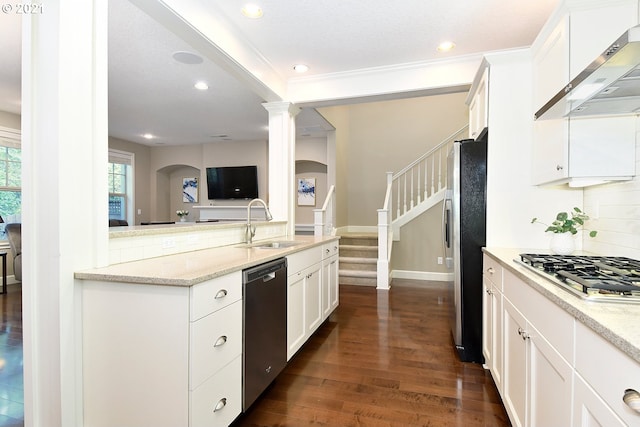 kitchen featuring light stone counters, white cabinetry, stainless steel appliances, and wall chimney range hood