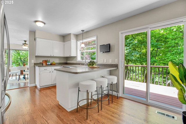 kitchen with a sink, a kitchen bar, white cabinetry, and a peninsula