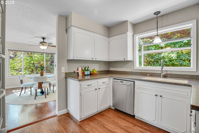 kitchen with dishwasher, a sink, ceiling fan, white cabinetry, and dark countertops