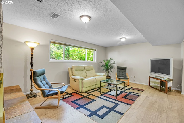living area featuring wood finished floors, a textured ceiling, and baseboards