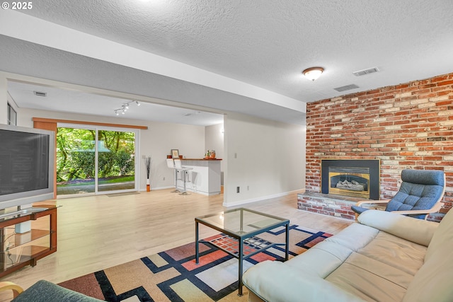 living room with wood finished floors, a textured ceiling, a fireplace, baseboards, and bar area