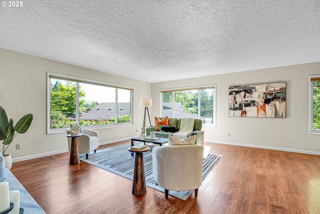 living area with a textured ceiling, hardwood / wood-style flooring, and baseboards