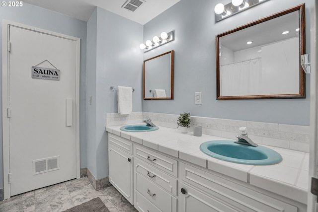 full bathroom with double vanity and baseboards