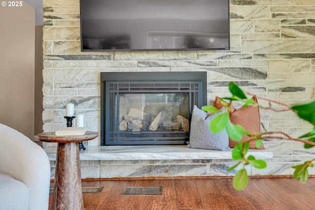 detailed view of wood finished floors and a stone fireplace