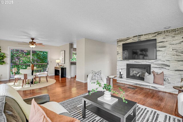 living area with wood finished floors, a fireplace, baseboards, and ceiling fan