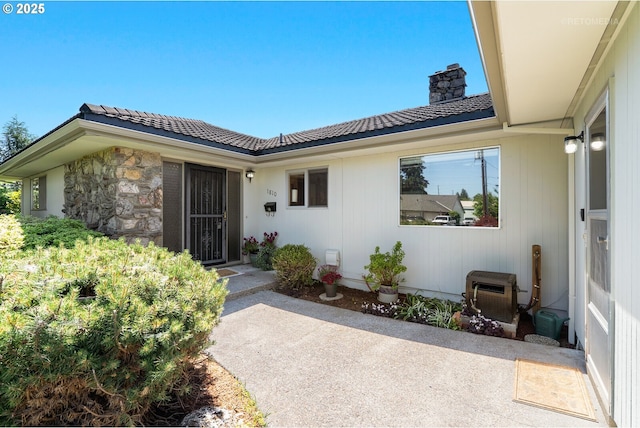 1810 D St, Forest Grove, OR 97116 - view of exterior entry featuring a patio area, a chimney, stone siding, and a tiled roof