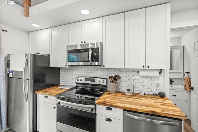 kitchen featuring wooden counters, appliances with stainless steel finishes, decorative backsplash, recessed lighting, and white cabinets