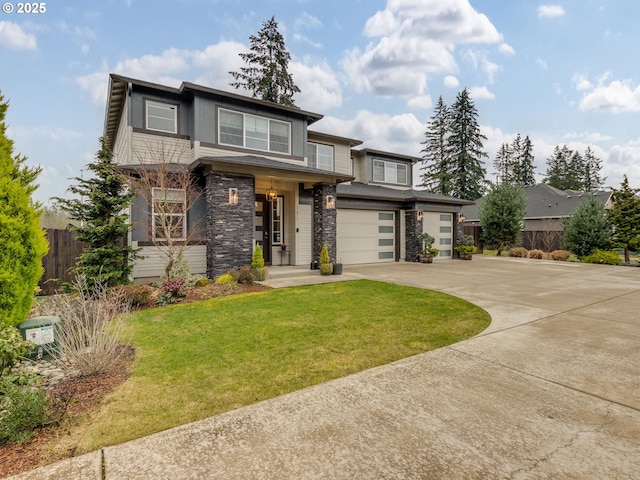 prairie-style house with fence, an attached garage, concrete driveway, a front lawn, and stone siding