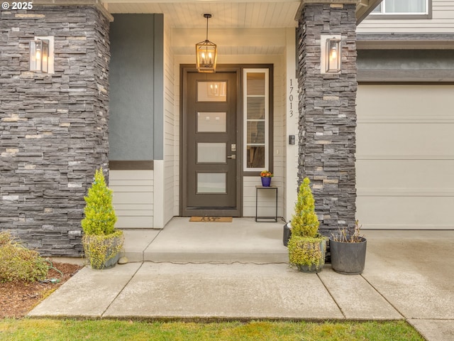 view of exterior entry featuring a porch, a garage, and stone siding