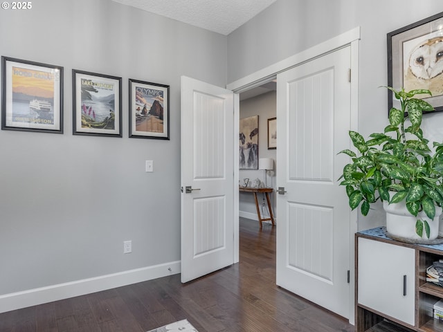 interior space featuring dark wood-style floors, baseboards, and a textured ceiling