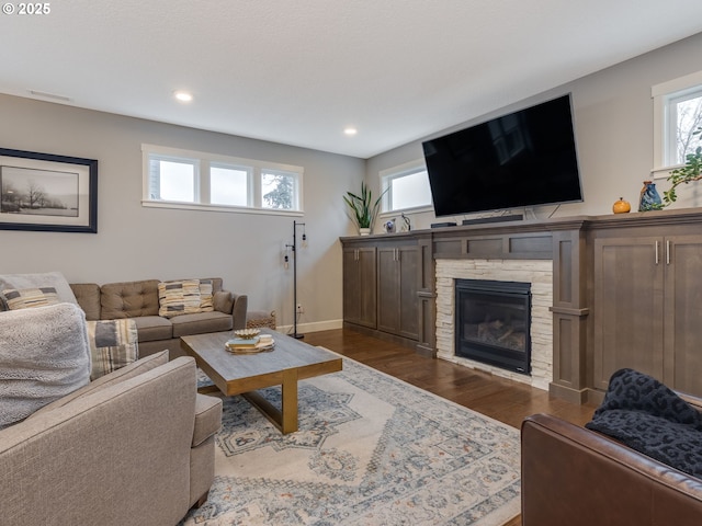 living area featuring a fireplace, dark wood-type flooring, recessed lighting, and a healthy amount of sunlight