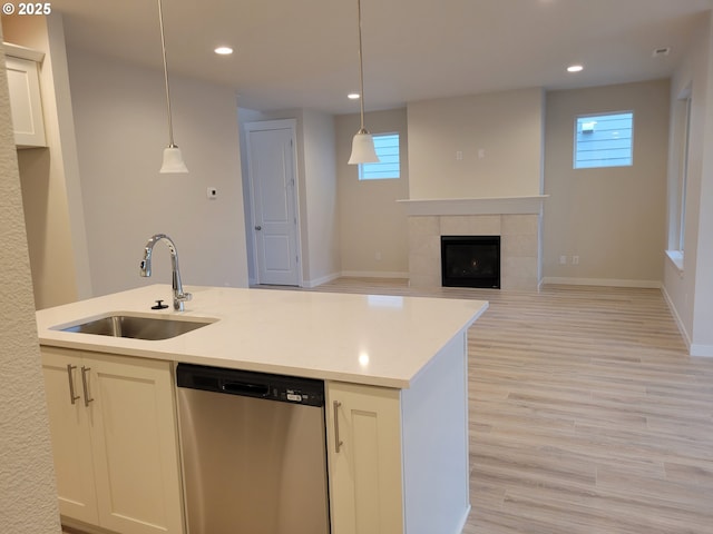 kitchen with a wealth of natural light, dishwasher, light wood-style flooring, a fireplace, and a sink