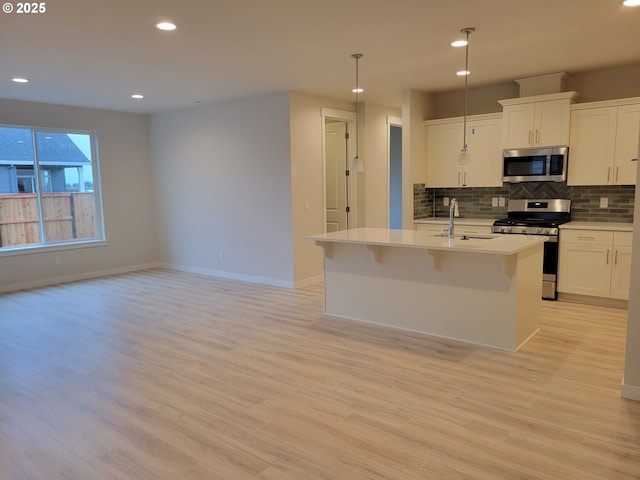 kitchen with stainless steel appliances, light countertops, backsplash, light wood-style floors, and a sink