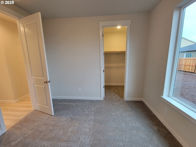 unfurnished bedroom with a closet, light colored carpet, and a spacious closet