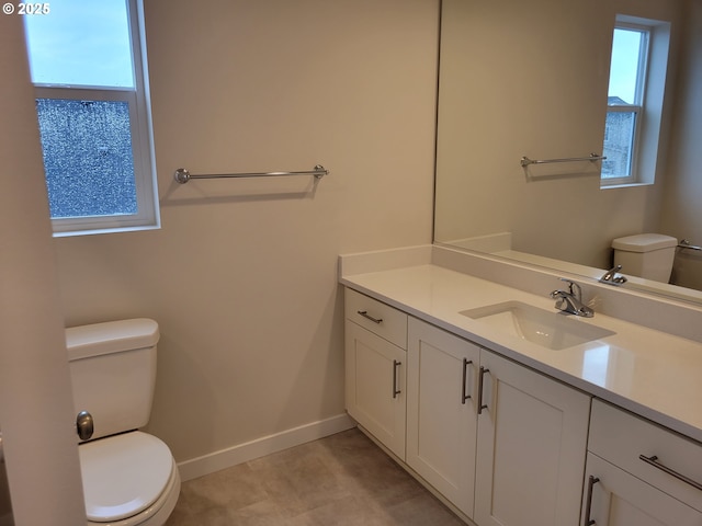 half bathroom featuring vanity, toilet, and baseboards