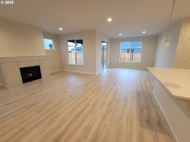 unfurnished living room with a healthy amount of sunlight, light wood-style floors, a fireplace, and recessed lighting