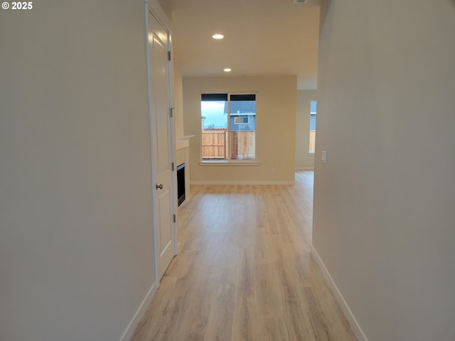 corridor featuring light wood-style flooring, baseboards, and recessed lighting