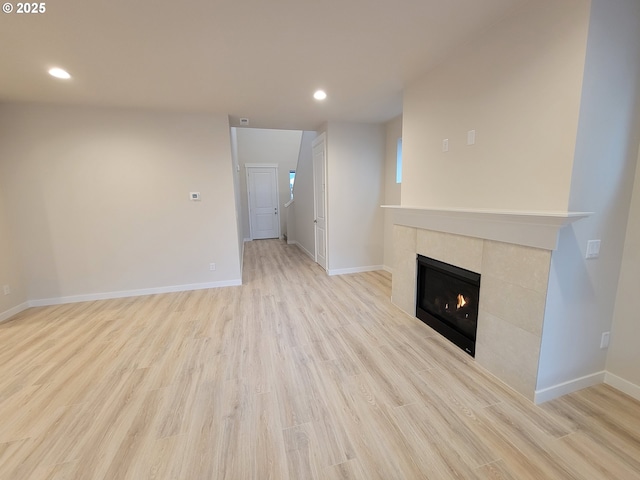 unfurnished living room featuring baseboards, recessed lighting, a fireplace, and light wood-style floors