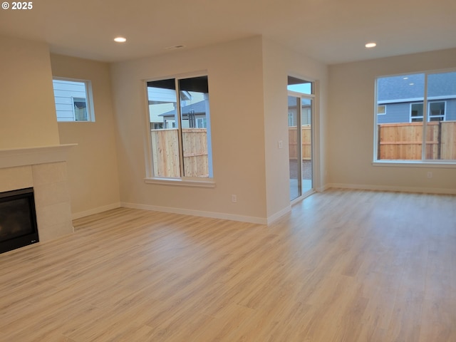 unfurnished living room featuring light hardwood / wood-style flooring and a tiled fireplace