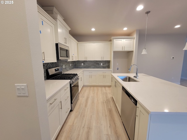 kitchen with a sink, white cabinetry, appliances with stainless steel finishes, decorative backsplash, and light wood finished floors