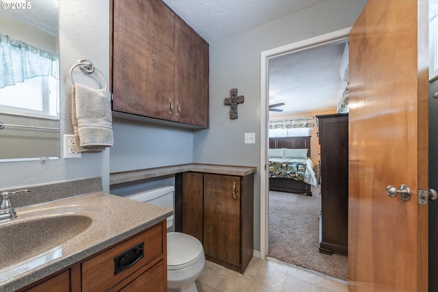 bathroom with toilet, a healthy amount of sunlight, vanity, and a textured ceiling