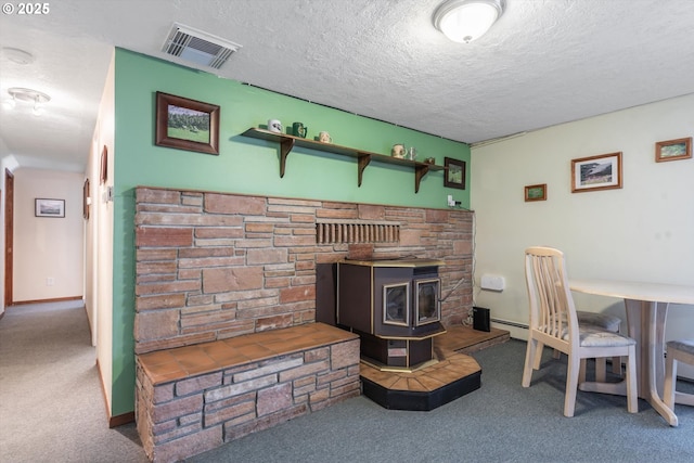 interior space with a wood stove, baseboards, visible vents, and a textured ceiling