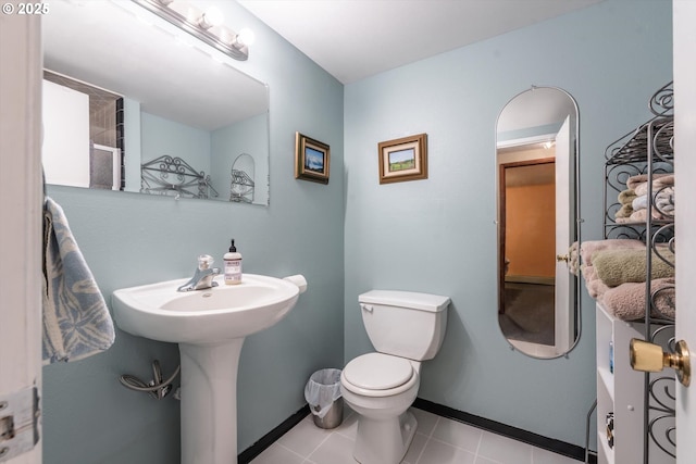 bathroom with a sink, baseboards, toilet, and tile patterned flooring