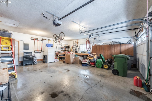 garage featuring electric panel, a workshop area, a garage door opener, and freestanding refrigerator