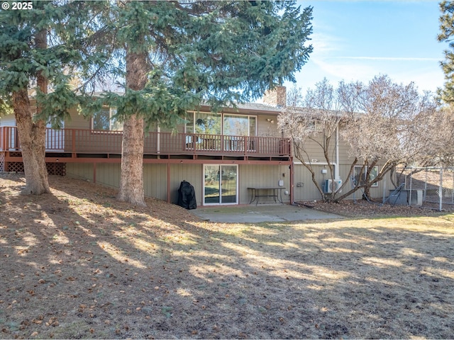 back of property with a deck, a patio area, and a chimney